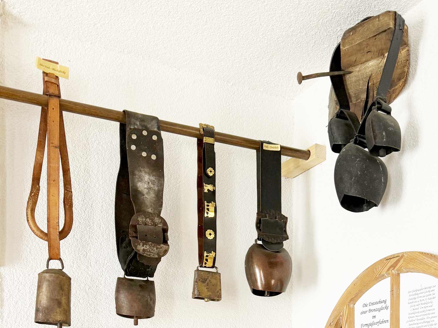 Kuhglocken mit verzierten Riemen an einer Ausstellungswand